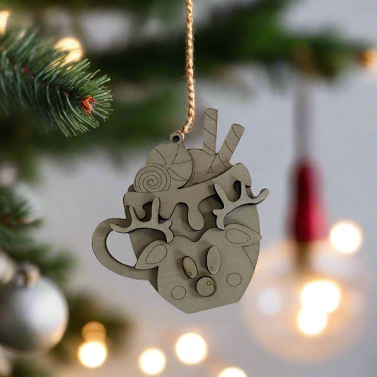 Decorative wooden ornament shaped like a teacup with Christmas elements hanging on a tree.